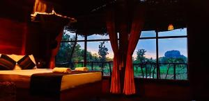 a bedroom with a bed and a large window at Chena Huts Eco Resort in Sigiriya