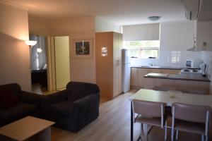 a living room with a couch and a table at Glenelg Holiday Apartments - Corfu in Adelaide