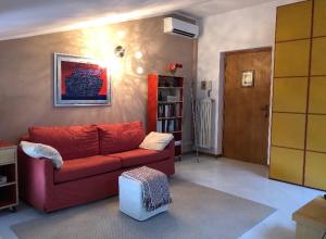 sala de estar con sofá rojo y estante para libros en La mansarda di Orni, en Ivrea