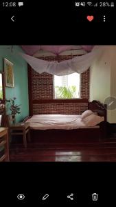 a bedroom with a bed and a window with curtains at Tien Yoga House in Cái Bè