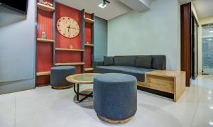 a living room with a couch and a table and a clock at Treebo Trend Lake Bloom Powai in Mumbai