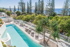 een uitzicht over een zwembad met palmbomen en de oceaan bij Sea Pearl A1 Beach Resort in Mooloolaba