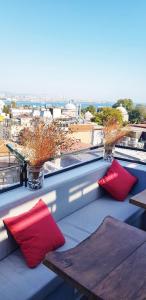 einen Balkon mit roten Kissen und Tischen auf dem Dach in der Unterkunft Nomade Old City Hotel in Istanbul