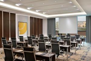 voco Al Khobar, an IHG Hotel في الخبر: قاعة اجتماعات مع طاولات وكراسي وشاشة