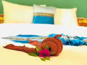 a pair of towels and a flower on a bed at Rimsuan House in Ko Lanta