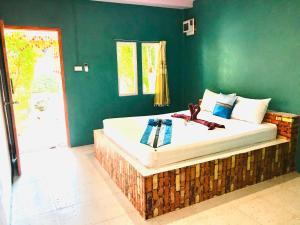 1 dormitorio con 1 cama grande y pared verde en Rimsuan House, en Ko Lanta
