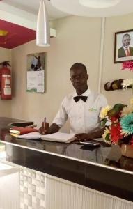 Un hombre con pajarita sentado en un mostrador en Jabali Country Lodge, en Kabondo