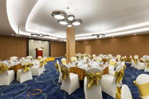 un salón de banquetes con mesas blancas y arcos amarillos en Grand Palace Hotel, en Yangón