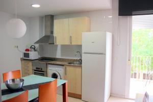 a kitchen with a white refrigerator and a table at Apartamentos Caru in Castelldefels