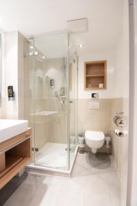 uma casa de banho com uma cabina de duche em vidro e um WC. em Nordsee-Hotel Hinrichsen em Husum