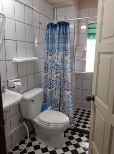 a bathroom with a toilet and a blue shower curtain at NB House in Karon Beach