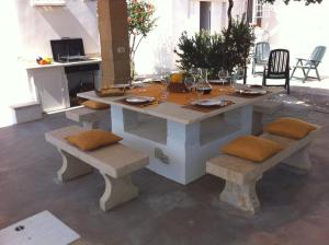 a table with cushioned benches and a table and chairs at Villa On The Beach "Spiaggia Plaia" in Castellammare del Golfo