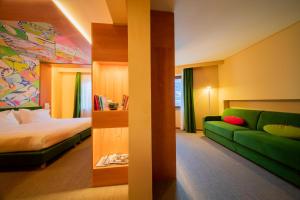 Habitación de hotel con cama y sofá verde en OMAMA Hotel en Aosta