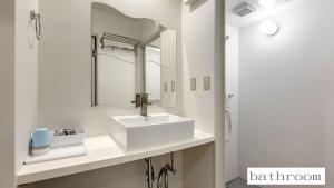 La salle de bains est pourvue d'un lavabo blanc et d'un miroir. dans l'établissement 玉出104 wifi付 玉出駅から徒歩2分 地下鉄難波迄8分, à Osaka