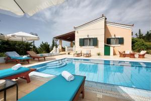 a swimming pool with chairs and tables next to a house at Villa AnnaMaria in Kastéllion