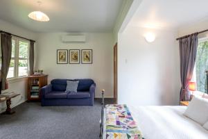 een slaapkamer met een bed en een blauwe bank bij Post Office Cottage - Self catering, escape to the country in Egmont Village