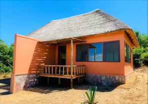 uma pequena casa laranja com telhado de palha em Kikonko Lodge em Biseruka