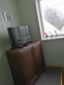 a flat screen tv on top of a wooden cabinet with a window at Liiva Guest Accommodation in Tartu