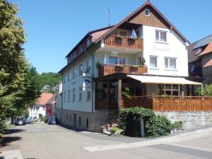 a large white building with a balcony on a street at Restaurant - Pension Herrgottstal in Creglingen