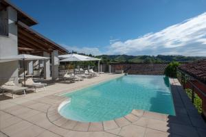 a swimming pool with chairs and umbrellas on a patio at Cascina Meriame in Serralunga d'Alba