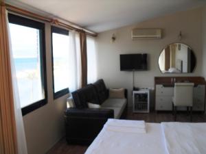 a room with a bed and a couch and a mirror at Kerman Hotel in Cesme