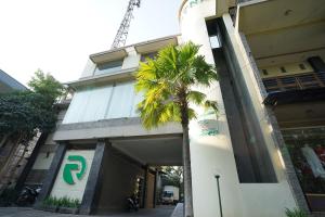 een gebouw met een palmboom ervoor bij Capital O 1430 Hotel Ratna Syariah in Probolinggo