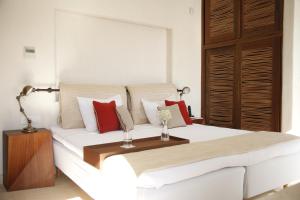 sypialnia z dużym białym łóżkiem z czerwonymi poduszkami w obiekcie Belvedere Mykonos - Waterfront Villa & Suites - The Leading Hotels of the World w mieście Mykonos +33 zdjęcia