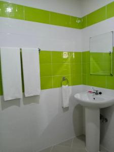 a bathroom with a white sink and green tiles at Chiangkham Grand Villa - SHA Certified in Chiang Kham