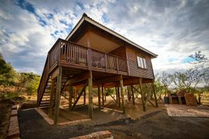ein aus Holz erbautes Haus mit einer umlaufenden Veranda in der Unterkunft Sangiro Game Lodge in Bloemfontein