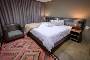 um quarto de hotel com uma cama e uma cadeira em Sangiro Game Lodge em Bloemfontein