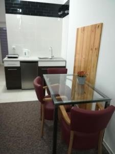 kuchnia ze szklanym stołem i krzesłami w obiekcie Buko apartamenty w Uniejowie