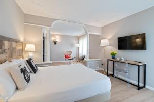 - une chambre avec un grand lit blanc et un bureau dans l'établissement Hotel Leon d'Oro, à Rovereto