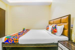 ein Schlafzimmer mit einem großen weißen Bett mit bunten Kissen in der Unterkunft FabHotel Aayash in Kalkutta