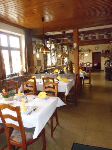 une salle à manger avec des tables, des chaises et un tissu de table blanc dans l'établissement Restaurant - Pension Herrgottstal, à Creglingen