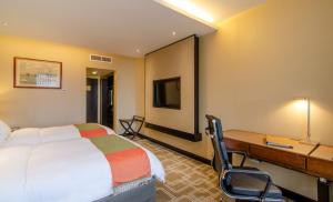a hotel room with a bed, chair, desk and a television at Pan Pacific Sonargaon Dhaka in Dhaka