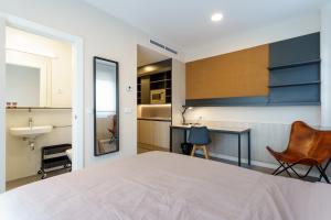 a bedroom with a large white bed and a kitchen at Residencia Universitaria Campus Málaga in Málaga