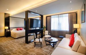 a hotel room with a bed and a television at Pan Pacific Sonargaon Dhaka in Dhaka