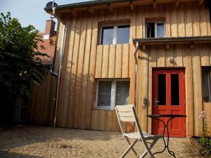 una silla sentada frente a una casa con una puerta roja en Töpferhof 1, en Tangermünde