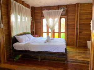 ein Schlafzimmer mit einem Bett mit weißen Laken und einem Fenster in der Unterkunft Sano Houes in Sukhothai