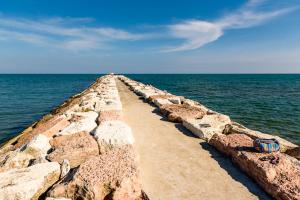 een lange stenen weg die naar de oceaan leidt bij Dune Agriturismo in Eraclea Mare