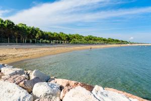 a beach with rocks in the water and trees at Dune Agriturismo in Eraclea Mare