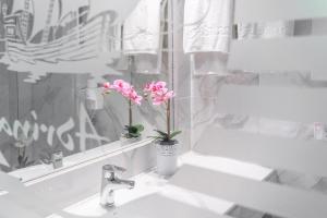 a white bathroom with a sink and a mirror at Adrina Beach Hotel in Panormos Skopelos