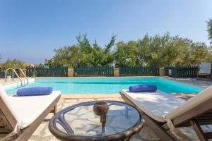 a swimming pool with a table and two chairs and a table sidx sidx at Kostas Cottages in Agios Nikolaos