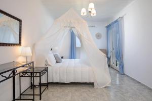 a bedroom with a white bed with a canopy at Kostas Cottages in Agios Nikolaos