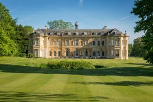 una antigua mansión en un campo verde con árboles en Hartwell House & Spa en Aylesbury