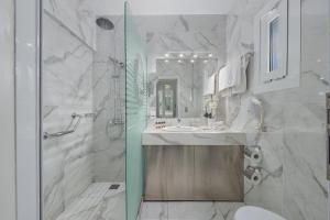 a white bathroom with a shower and a sink at Adrina Beach Hotel in Panormos Skopelos