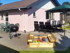a patio with a table and chairs and a grill at 5 person holiday home in V ggerl se in Marielyst