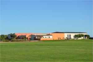a house in the middle of a green field at Trafalgar Polo Club in El Palmar