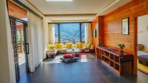 a living room with yellow chairs and a large window at The Postcard Dewa, Thimphu, Bhutan in Thimphu