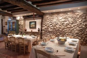 a dining room with tables and chairs and a stone wall at La Casona del Pastor in Valgañón